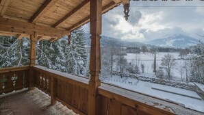 Un balcón de madera con vistas a un paisaje nevado y montañas.