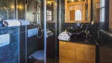 Une salle de bain moderne avec une douche à parois de verre, un meuble-lavabo en bois avec un lavabo noir et un miroir au-dessus du lavabo.