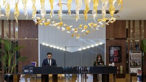 Un comptoir d’accueil au design moderne, un panneau indiquant la zone d’accueil et un écran numérique affichant des informations.