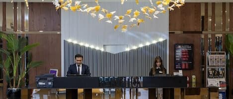 Un mostrador de recepción de diseño moderno, un cartel que indica la zona de recepción y una pantalla digital mostrando información.