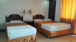 A hotel room with two single beds, a nightstand with a telephone, and two wall-mounted lamps. - Hotel Don Felipe (Ormoc)