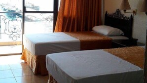 A hotel room with two single beds, a window with curtains, a view of the city, and a bed with a headboard. - Hotel Don Felipe (Ormoc)