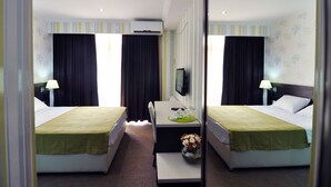 A hotel room with two beds, a desk, a TV, and a mirror. - Green Panorama (Tbilisi)