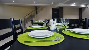 A dining area with tables set for four, each with white plates, green placemats, and wine glasses. - Green Panorama (Tbilisi)