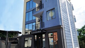 A modern hotel named "Panorama" with a prominent balcony, large windows, and a visible entrance. - Green Panorama (Tbilisi)