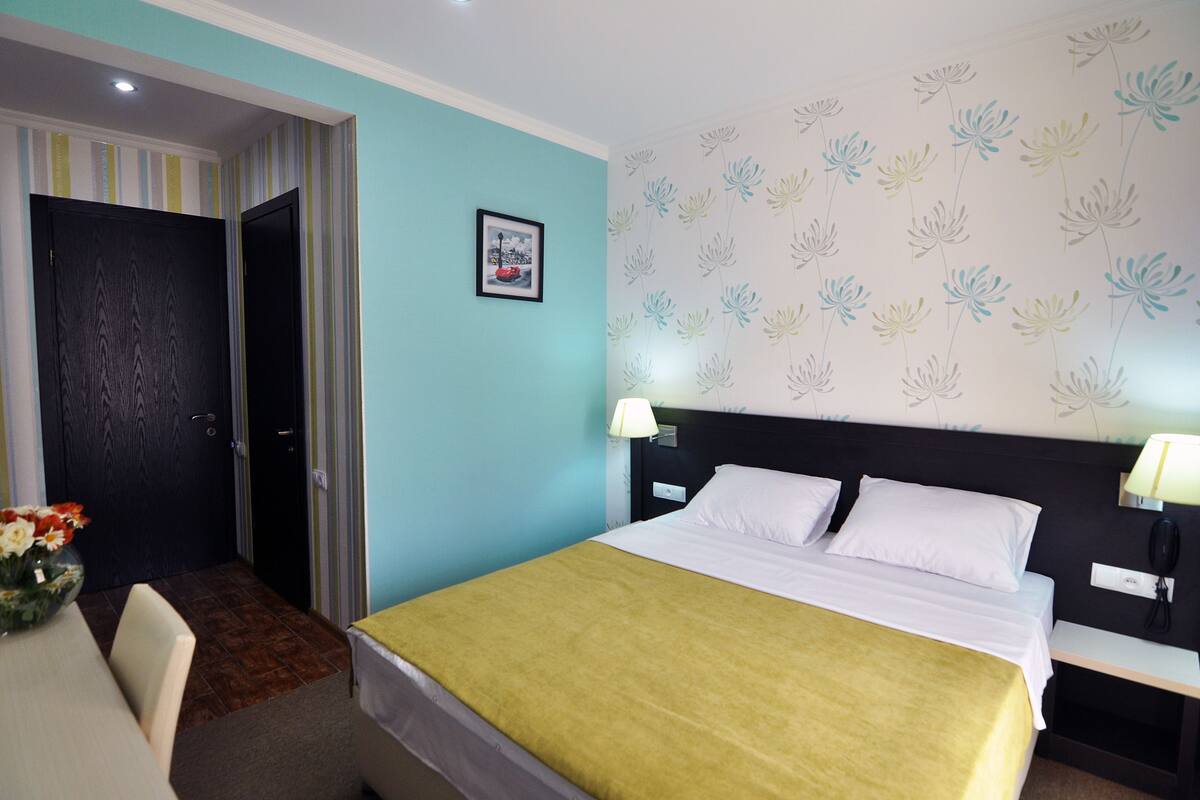 A hotel room with a bed, bedside tables, a desk, and a chair.