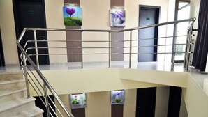 A hotel lobby with a staircase, a reception desk, and framed artwork on the walls. - Green Panorama (Tbilisi)