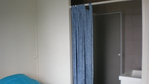 Une chambre avec un lit, une douche et un lavabo blanc.