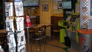 Un petit café avec un comptoir, des chaises et un téléviseur diffusant un événement sportif.