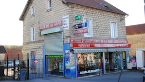 Un bâtiment à deux étages, sur lequel on peut lire l’enseigne « Café de la Gare » et « Restaurant ».