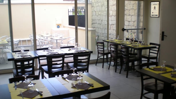 Un restaurant avec de nombreuses tables et chaises, dont certaines sont dotées de sets de table jaunes.
