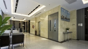 Eine moderne Hotellobby mit poliertem Boden, einer Rezeption, einer Sitzecke und einem Gemälde an der Wand.