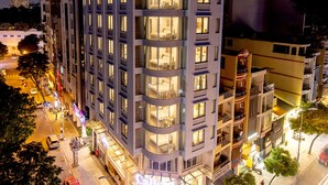 Ein mehrstöckiges Hotel mit modernem Design, das durch einen markanten Hauseingang, eine sichtbare Außenbestuhlung und eine gut beleuchtete Fassade besticht.