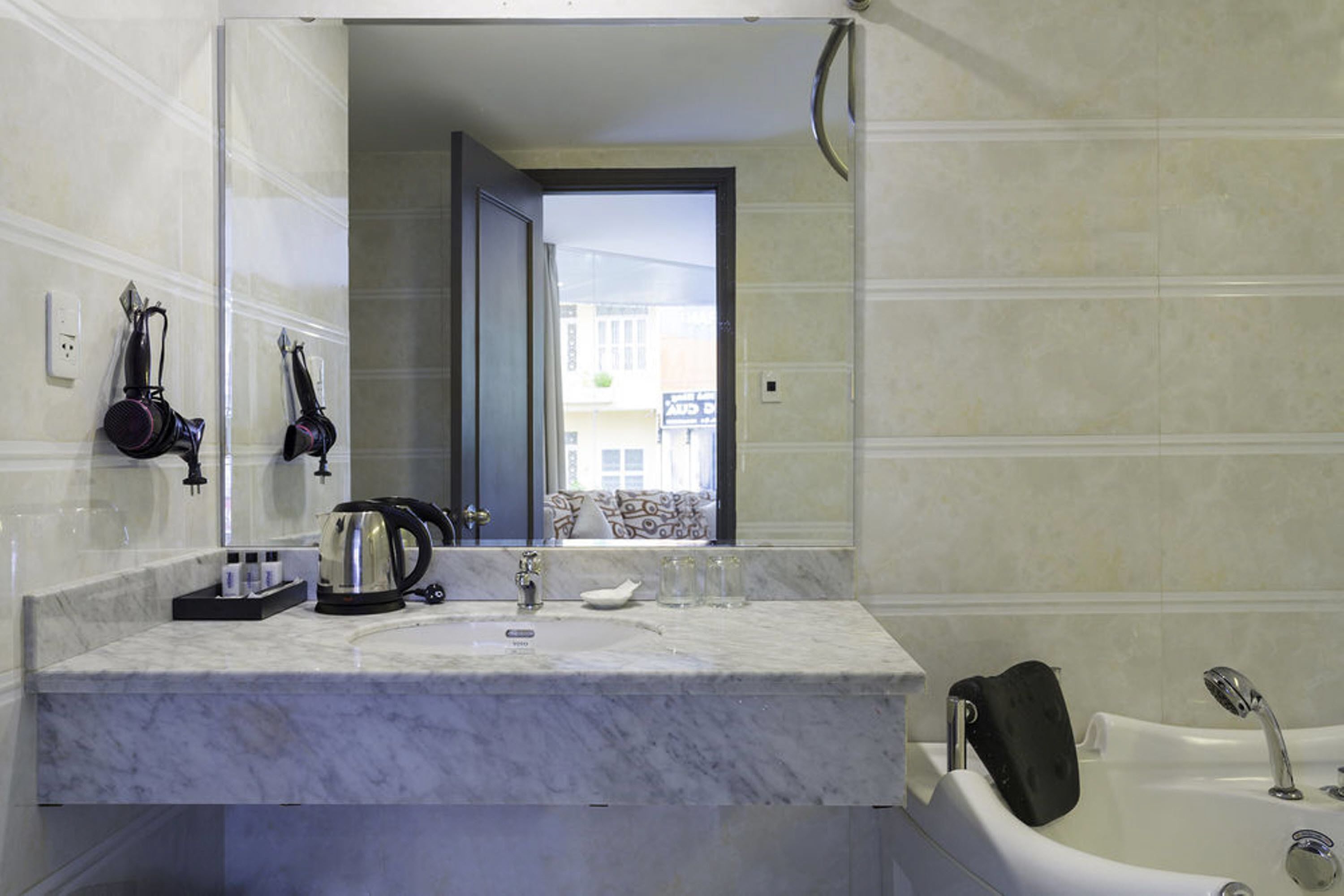 Un baño con lavamanos de mármol, cafetera y bañera.