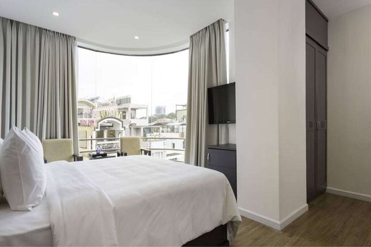 Une chambre d’hôtel équipée d’un lit, d’une télévision, d’un bureau et offrant une vue sur le paysage urbain.