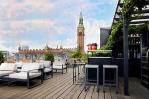 A rooftop terrace with outdoor seating, a bar area, and a view of a historic tower. - Boutique Hotel Danmark (Copenhagen)