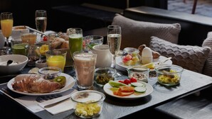 A breakfast table with various dishes and drinks, a window with a view of the outside, and a red chair in the background. - Boutique Hotel Danmark (Copenhagen)
