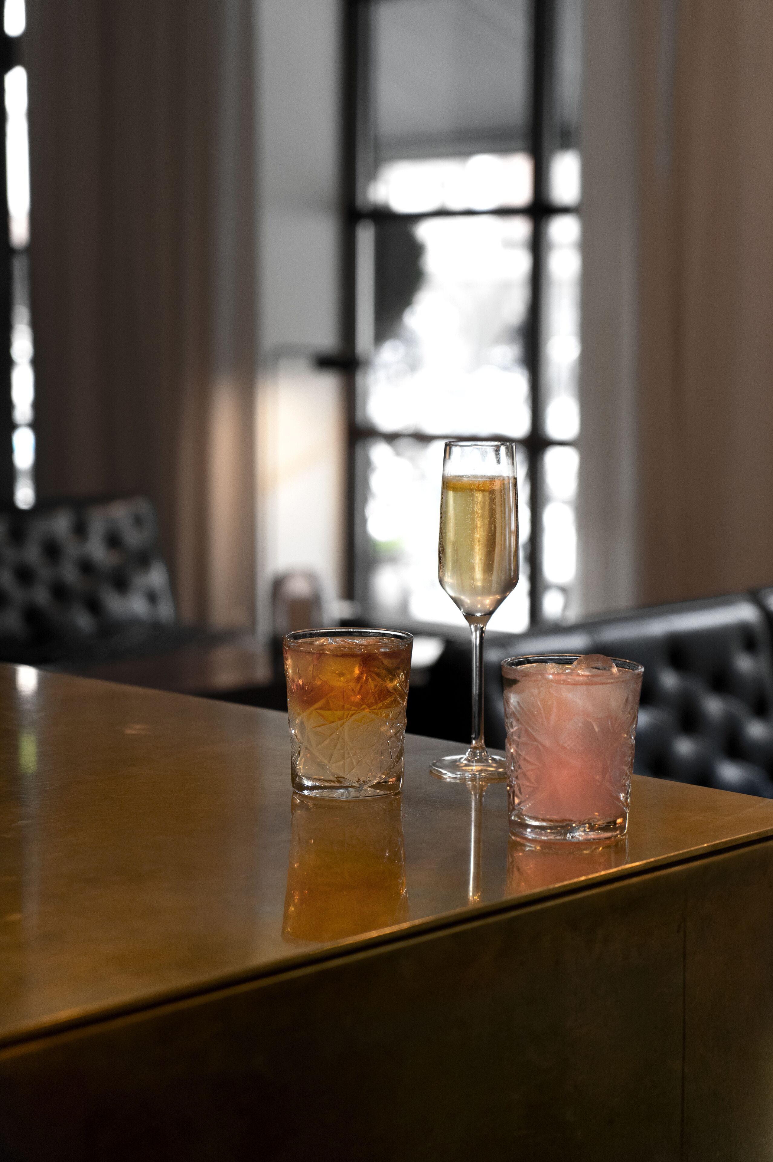 Een bar met twee glazen drank op een houten toonbank.