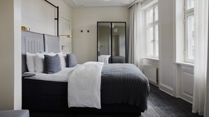 A modern hotel room with a large bed, a mirror, and a window with curtains. - Boutique Hotel Danmark (Copenhagen)