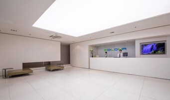 A modern reception area with a flat-screen TV, a reception desk, and a seating area with benches.