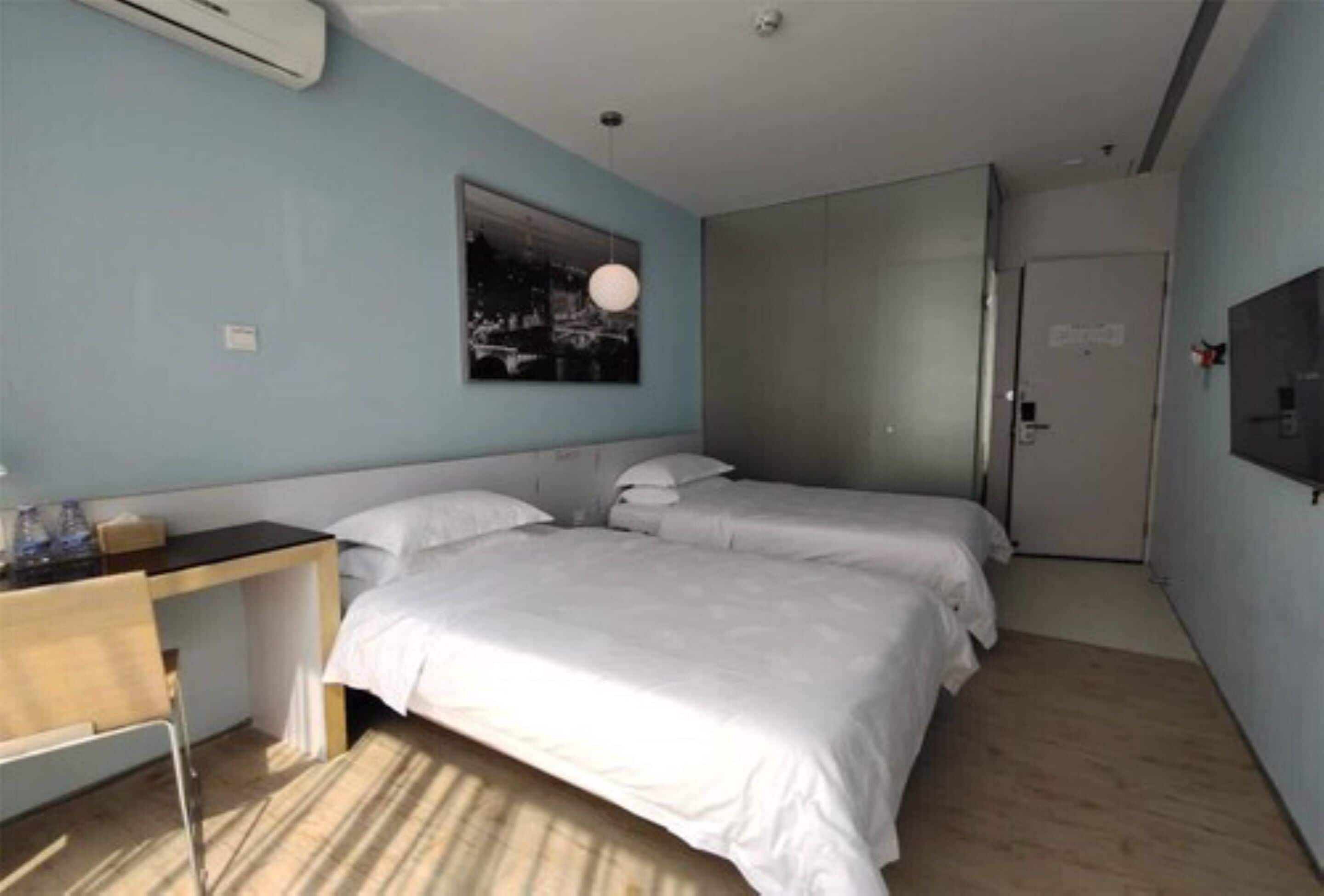 Une chambre d’hôtel avec deux lits, un bureau et une grande fenêtre.