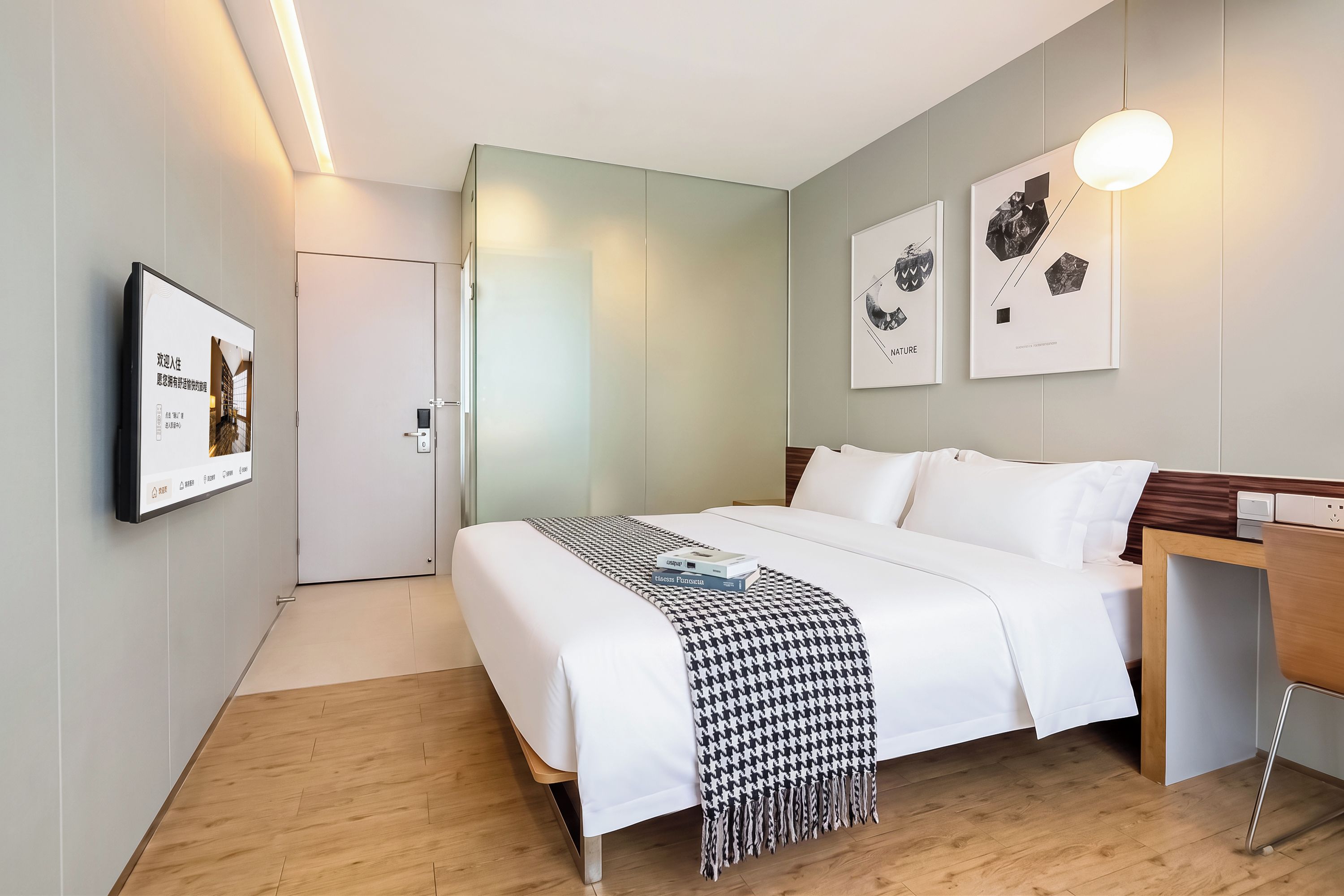 A modern hotel room with a bed, bedside table, and a wall-mounted TV.