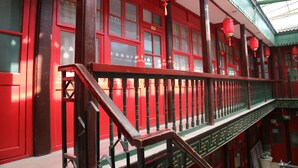 A traditional building with red doors and a balcony with a wooden railing.