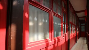 A corridor with red-painted walls and large windows.