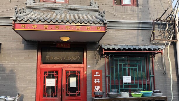A traditional building with a red door and a sign indicating it is a hostel.