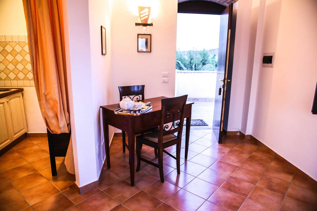 Un coin repas avec une table et des chaises, une fenêtre donnant sur un paysage agréable et une porte menant à l’extérieur.