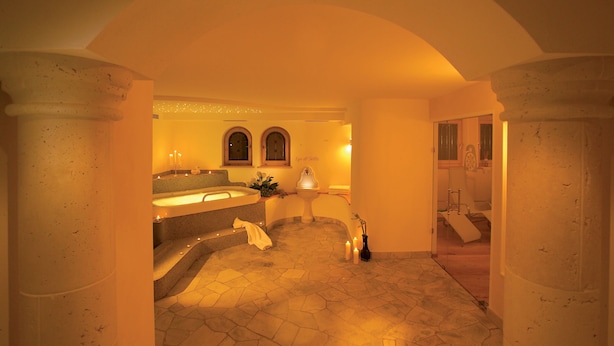 A luxurious bathroom with a stone floor, a bathtub, and a sink. - Hotel Armin (Selva di Val Gardena)
