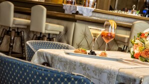 A dining area with a table set for two, featuring a bottle of wine, a martini glass, and a small appetizer. - Hotel Armin (Selva di Val Gardena)
