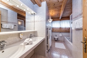 Un baño moderno con un lavamanos grande, espejo y zona de ducha.