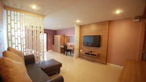 A modern living room with a sofa, a TV mounted on the wall, and a wooden cabinet. - Pintree Service Apartment Pattaya (Pattaya)