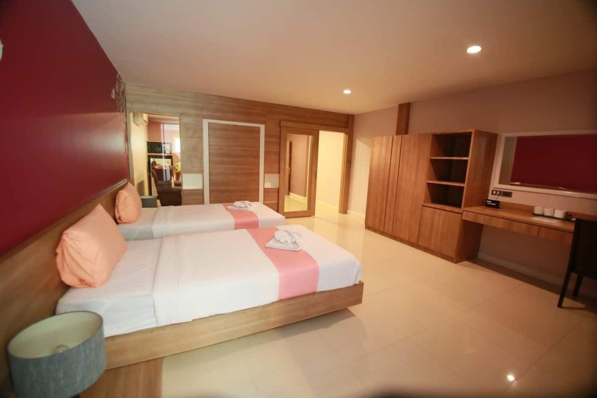 A hotel room with two beds, a desk, a TV, and a wardrobe.