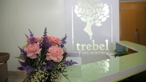 Uma mesa de recepção com um arranjo floral e o logotipo da 'trebel' ao fundo.