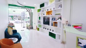 Uma área de recepção com uma mesa de vidro, uma televisão e uma estante de livros.