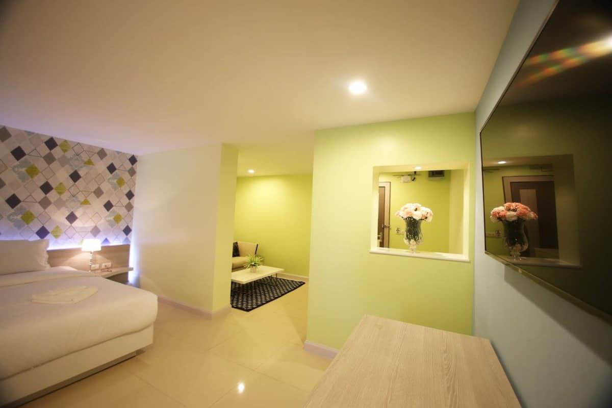 Una camera d'albergo con un letto, un tavolino, uno specchio e una finestra con fiori.