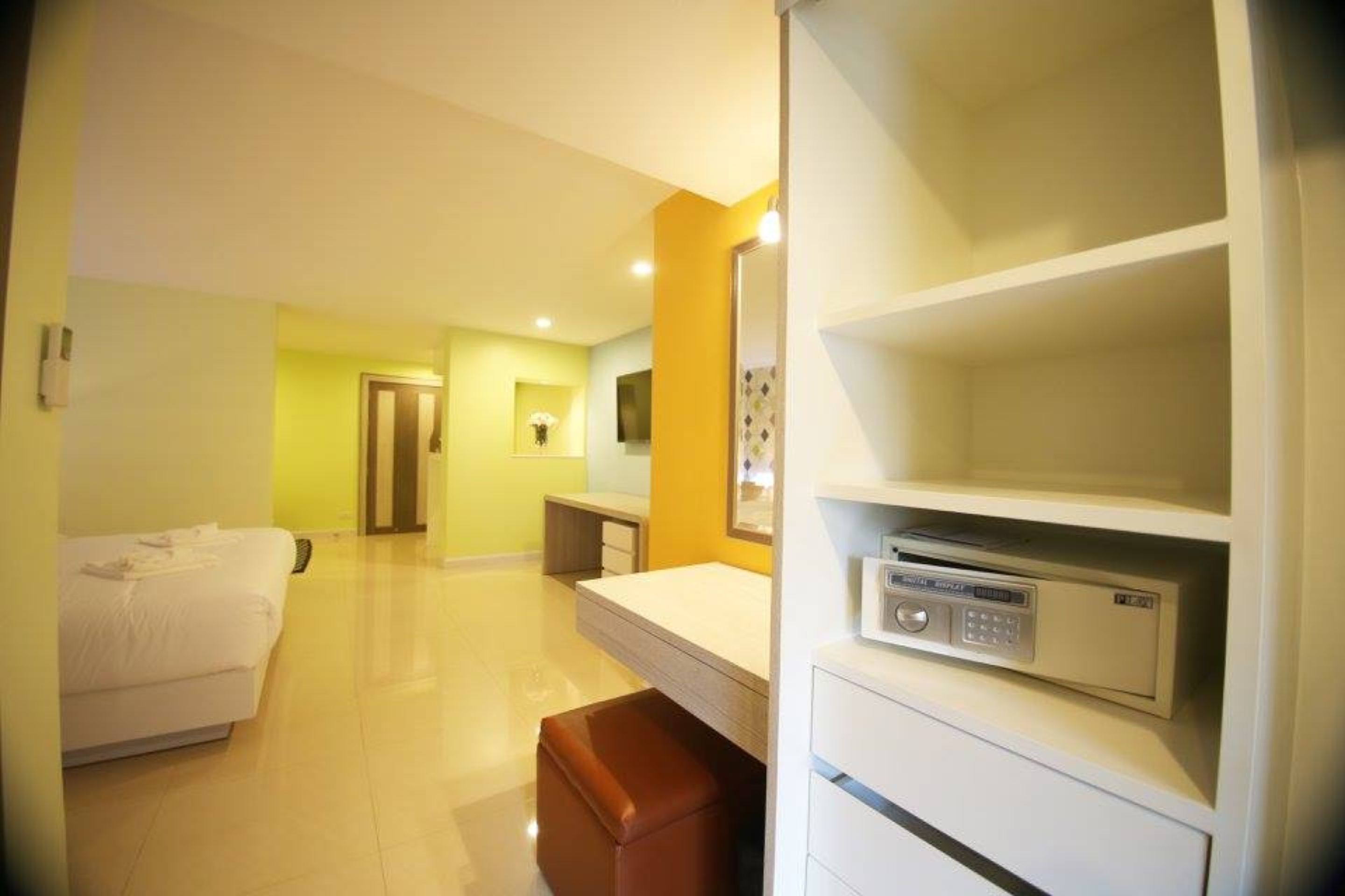 Camera d'albergo con un letto, una scrivania, uno specchio e un minibar.