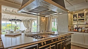 A modern kitchen with a large island, stainless steel appliances, and a view of the outdoors. - Villa Dora (San Gimignano)
