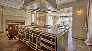 A spacious kitchen with a large island, modern appliances, and a view of the outdoors. - Villa Dora (San Gimignano)