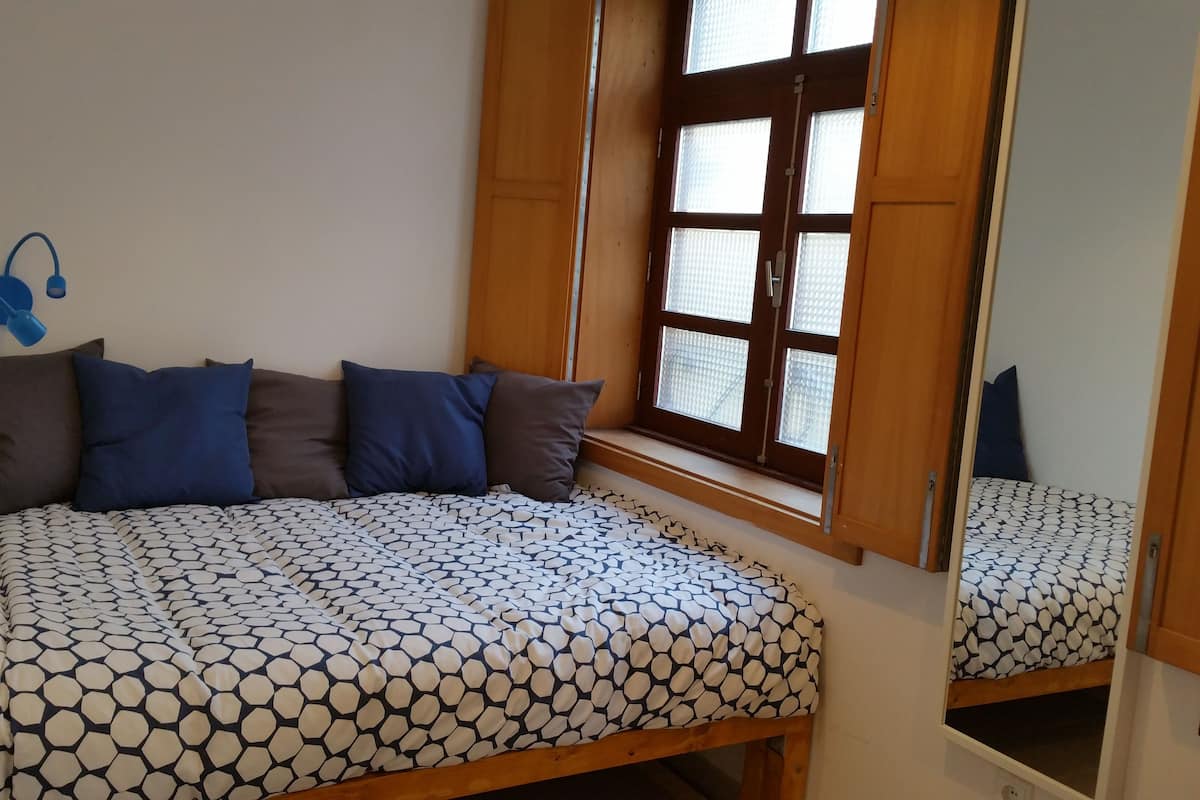 Un dormitorio con cama, ventana y espejo.