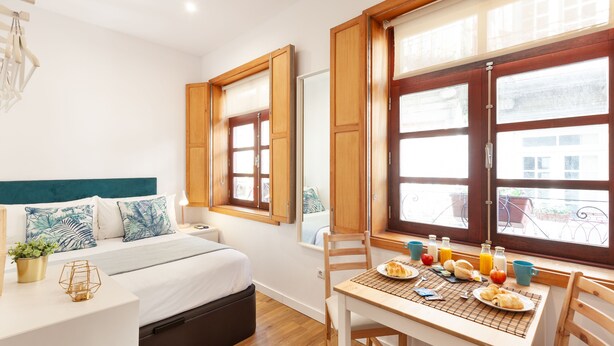 A bedroom with a bed, bedside table, and a window with curtains. - D&S - Porto São Bento Apartments I (Porto)