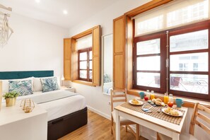 A bedroom with a bed, bedside table, and a window with curtains. - D&S - Porto São Bento Apartments I (Porto)