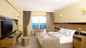 A hotel room with a bed, a desk, a TV, and a view of the ocean. - Gumuldur Resort Hotel & SPA (Menderes)