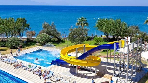 A water park with a pool and slides, surrounded by palm trees and a view of the sea. - Gumuldur Resort Hotel & SPA (Menderes)