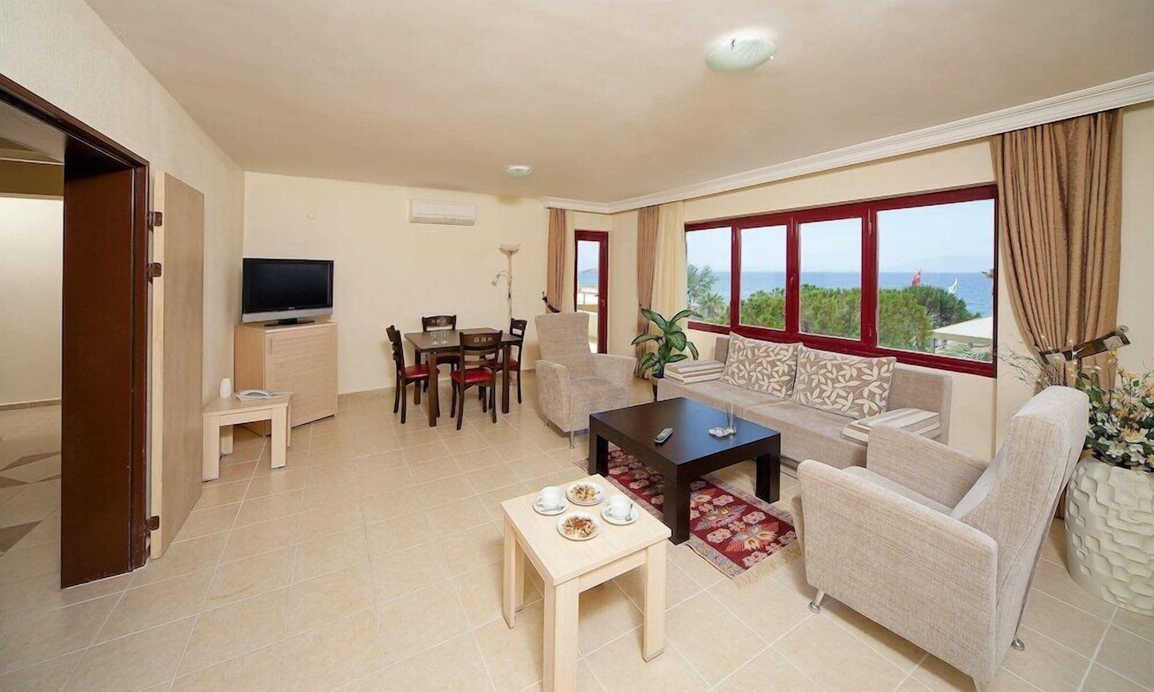Een woonkamer met televisie, bank, eettafel en uitzicht op zee.