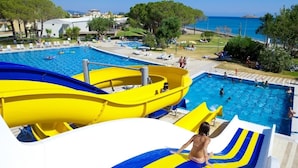 A large outdoor swimming pool with multiple slides and a view of the sea. - Gumuldur Resort Hotel & SPA (Menderes)