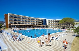 Un hotel con una gran piscina, tumbonas y una zona cubierta.