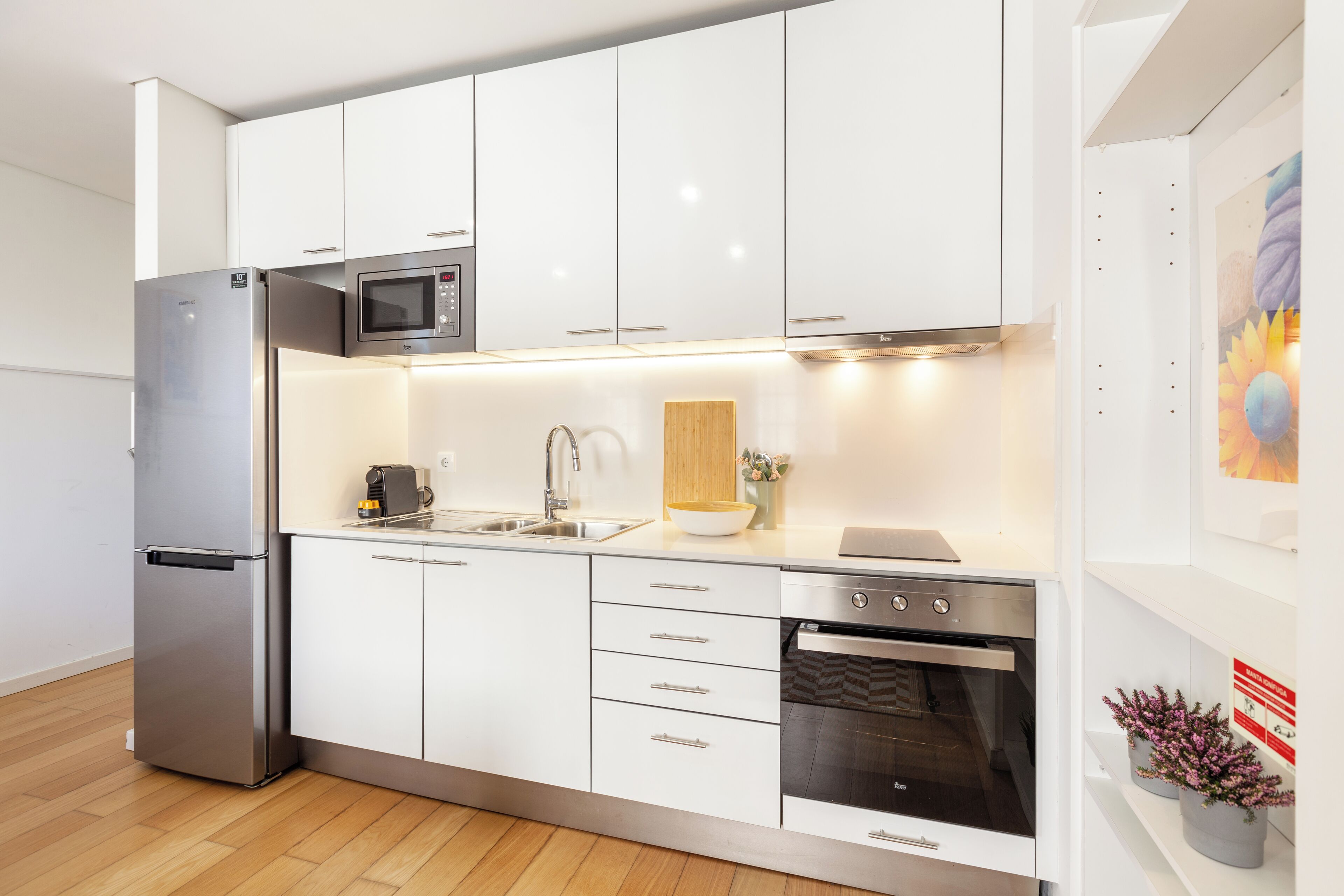 Une cuisine moderne avec des armoires blanches, des appareils en acier inoxydable et un plan de travail en bois.